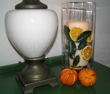 Декоративная свеча в глубокой вазе, украшенная помандерами из апельсинов и листьями лавра. 